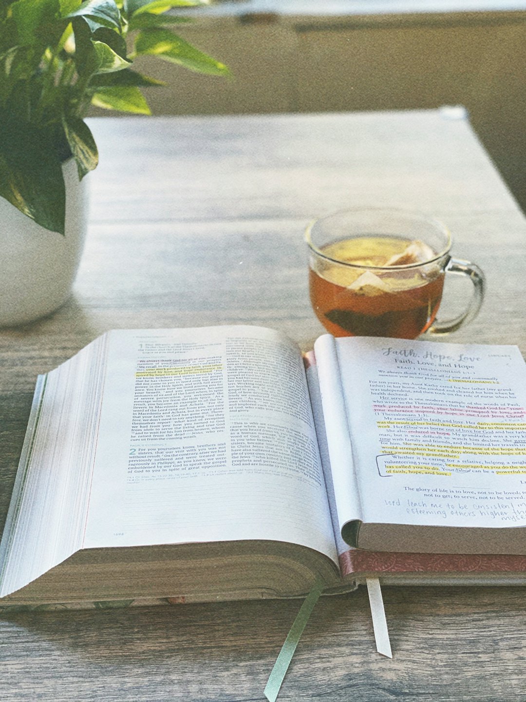 An open Bible and journal sit on a wooden table.